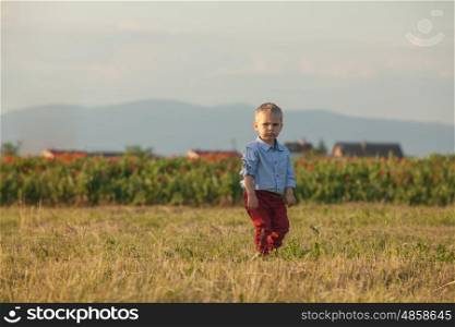 Portrait of a little cute boy in red pants on a rural background. Outdoor portrait of a cute little boy