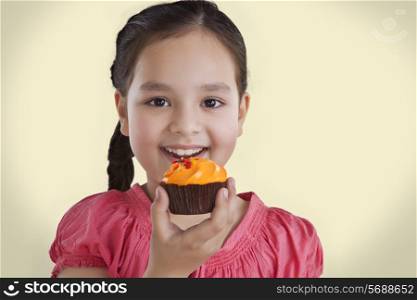 Portrait of a little girl eating a cupcake