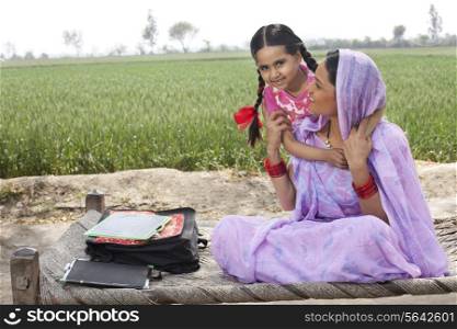 Portrait of a little girl embracing her mother with field in background