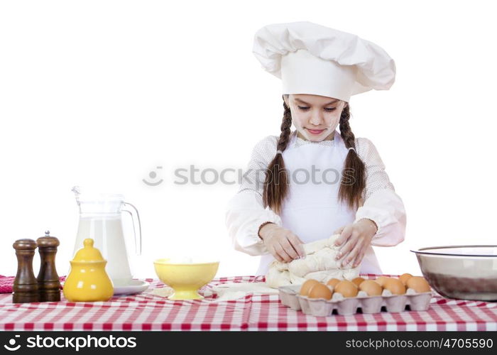 Portrait of a little girl in a white apron and chefs hat knead the dough in the kitchen, isolated on a white background