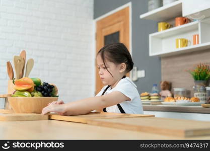 Portrait of a little girl in the kitchen of a house having fun playing with fruit toy and kitchenware