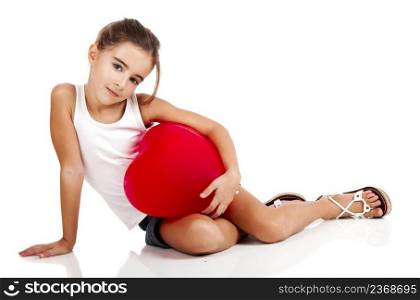 Portrait of a little girl sitting on floor and embracing a red balloon, isolated on white background