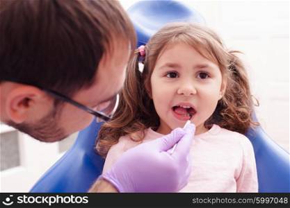 Portrait of a little girl that is sitting with his open mouth and checks the teeth at the dentist. The reception at the dentist