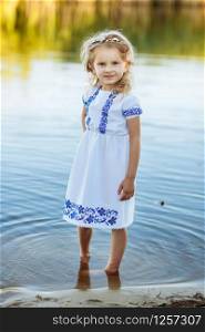 portrait of a little girl who stands in water in a white dress. beach in summer. portrait of a little girl who stands in water in a white dress. beach in summer.