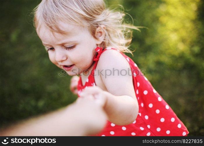 portrait of a little happy girl. the child holds the hand of the parent and plays