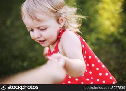 portrait of a little happy girl. the child holds the hand of the parent and plays