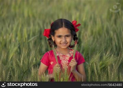 Portrait of a little Indian girl holding wheat stalks