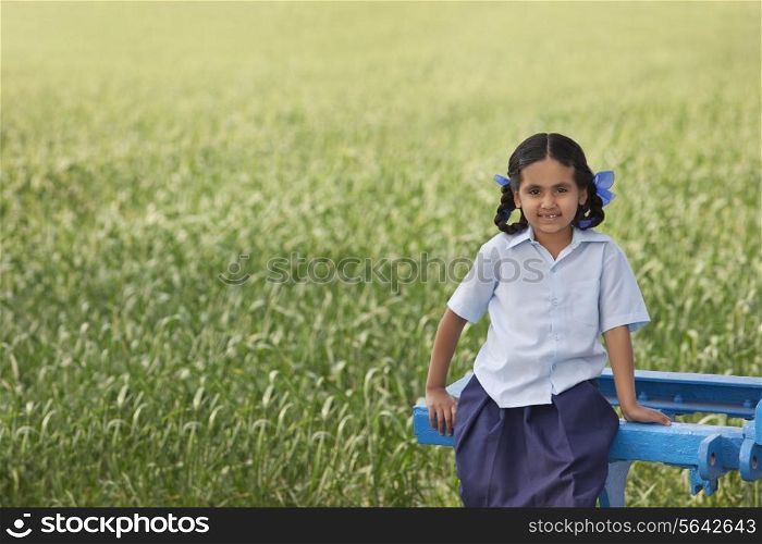 Portrait of a little rural school girl sitting in a field