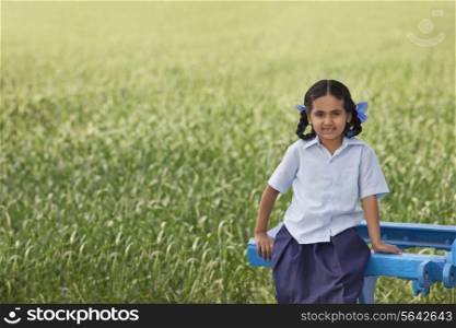 Portrait of a little rural school girl sitting in a field
