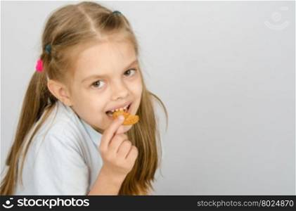 Portrait of a little six year old girl biting a cookie