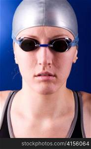 portrait of a looking at camera woman swimmer on blue background