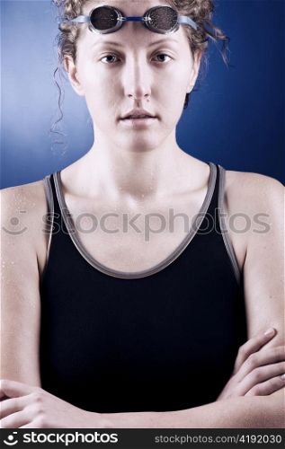 portrait of a looking at camera woman swimmer with folded hands, blue toned on blue background
