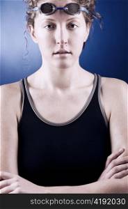 portrait of a looking at camera woman swimmer with folded hands, blue toned on blue background