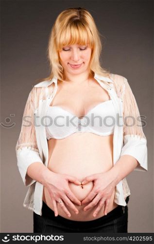 portrait of a looking down pregnant woman on grey background