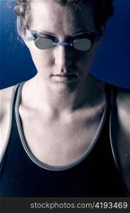 portrait of a looking downwards concentrated woman swimmer, blue toned on blue background