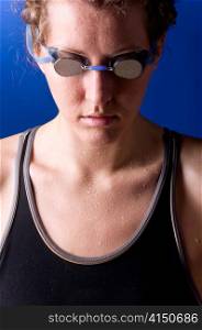 portrait of a looking downwards concentrated woman swimmer on blue background