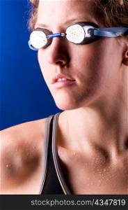 portrait of a looking sideways woman swimmer on blue background
