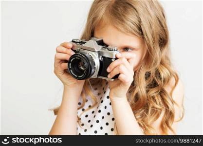 Portrait of a lovely little girl with old SLR film camera against a white background