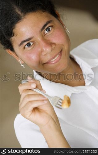 Portrait of a maid holding food in a fork and smiling