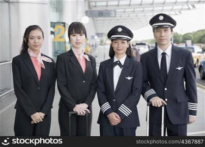 Portrait of a male and a female pilot standing with two cabin crew members