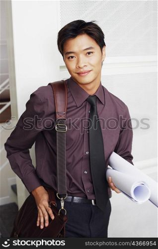 Portrait of a male architect holding rolled up blueprints and smiling
