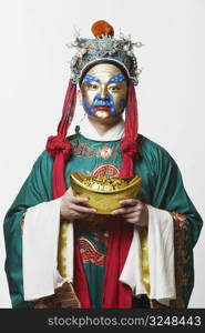 Portrait of a male Chinese opera performer holding a bowl full of gold coins