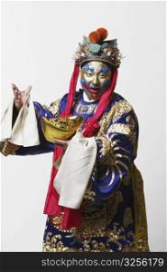 Portrait of a male Chinese opera performer holding a bowl full of gold coins
