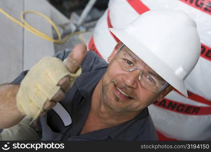 Portrait of a male construction worker showing a thumbs up sign and smiling