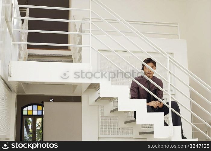 Portrait of a male customer service representative sitting on the staircase
