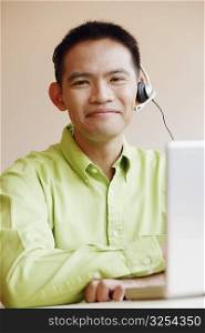 Portrait of a male customer service representative using a laptop and smiling