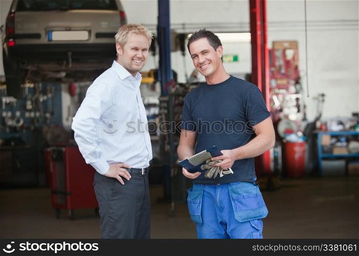 Portrait of a male customer standing with mechanic outside the garage