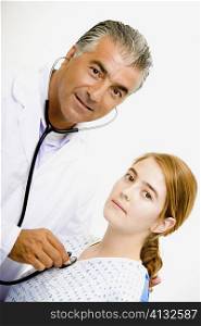 Portrait of a male doctor examining a young woman with a stethoscope