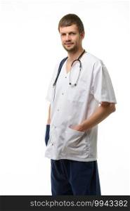 Portrait of a male doctor, hands stuck in pockets, a phonendoscope hangs around his neck, isolated on white background