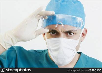 Portrait of a male doctor holding protective eyewear