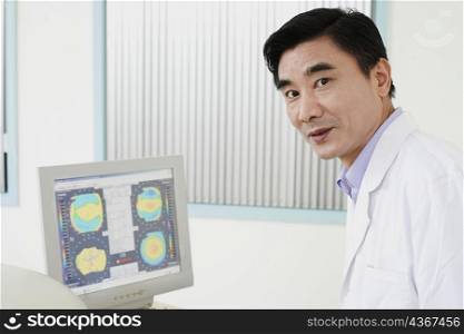 Portrait of a male doctor in front of a computer monitor