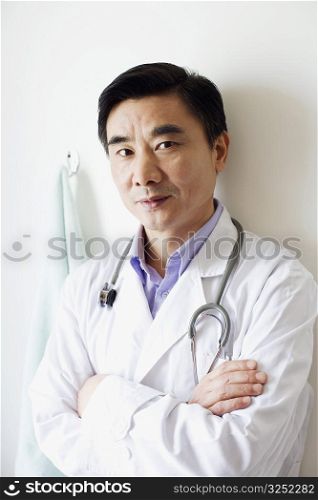 Portrait of a male doctor leaning against a wall