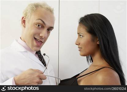 Portrait of a male doctor pulling a young woman with a stethoscope