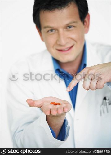 Portrait of a male doctor showing pills on his palm