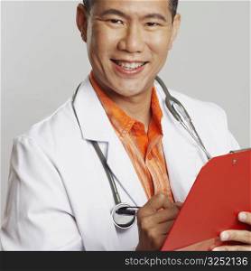 Portrait of a male doctor writing on a clipboard and smiling