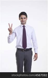 Portrait of a male executive giving peace sign