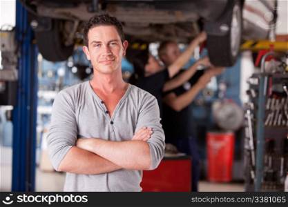 Portrait of a male mechanic looking at the camera with workers in the background