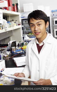 Portrait of a male pharmacist holding a document in a laboratory