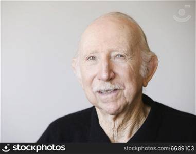 Portrait of a male senior citizen against a white background.