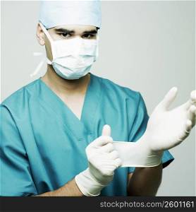 Portrait of a male surgeon putting on surgical gloves