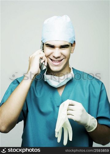 Portrait of a male surgeon smiling and using a mobile phone