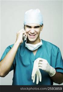 Portrait of a male surgeon smiling and using a mobile phone