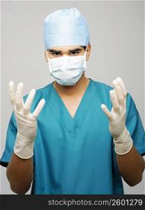Portrait of a male surgeon wearing a surgical mask and surgical gloves