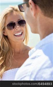 Portrait of a man and woman romantic couple with perfect teeth wearing white clothes and sunglasses on a beach. Woman Man Couple Wearing Sunglasses on a Beach