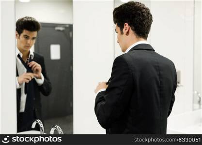 Portrait of a man getting dressed in a public restroom with mirror