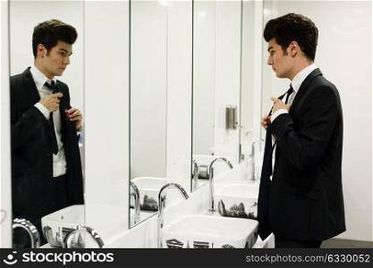 Portrait of a man getting dressed in a public restroom with mirror
